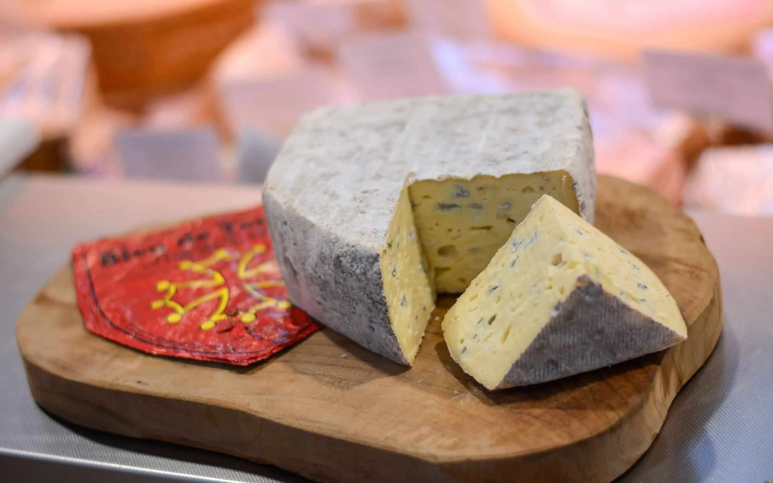 Un fromage à croûte cendrée entamé sur une planche