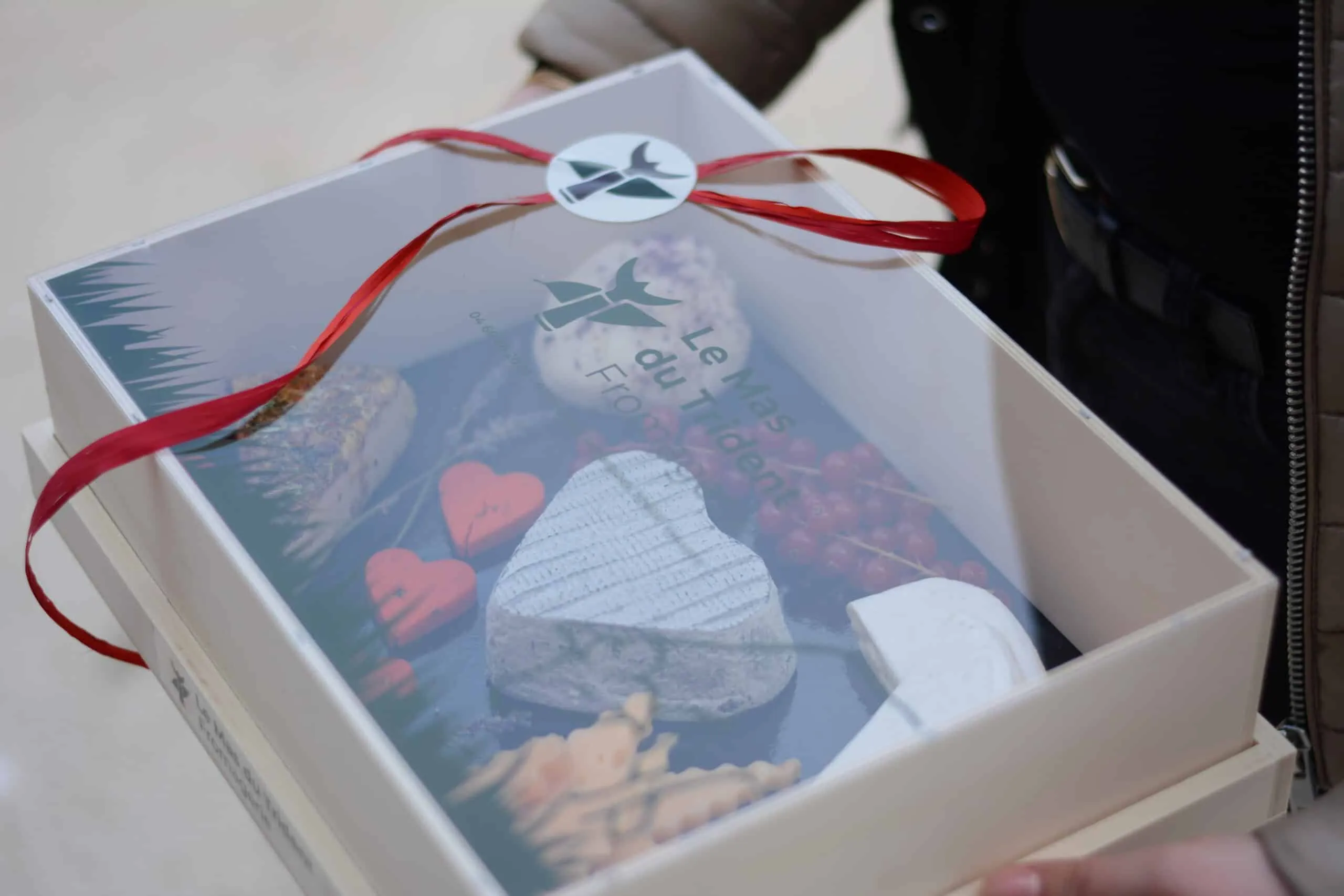 Un coffret de fromages fermé d’un ruban rouge