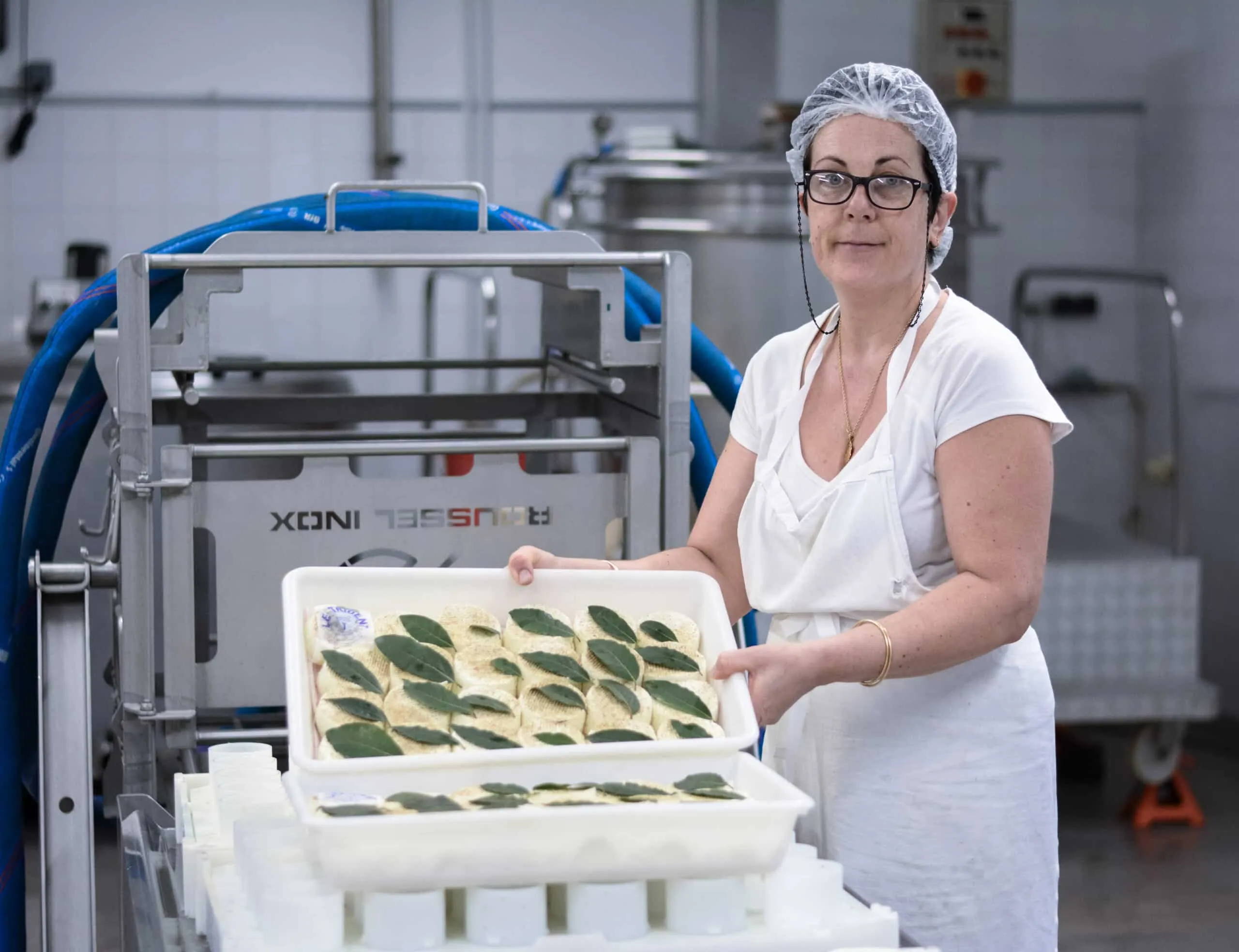 Une fromagère porte un bac de Tridents frais décorés de laurier
