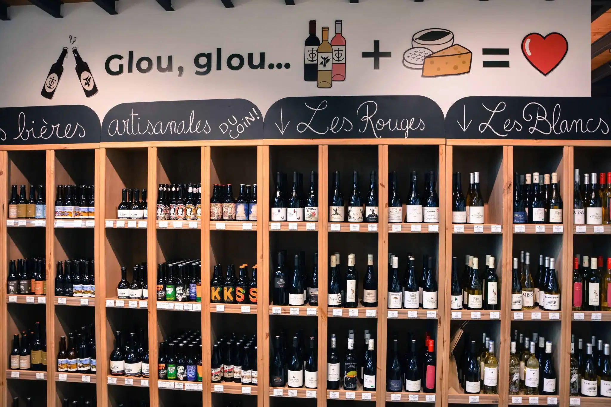 Le rayon cave de la boutique, bières artisanales et vins rouges et blancs sur des casiers de bois
