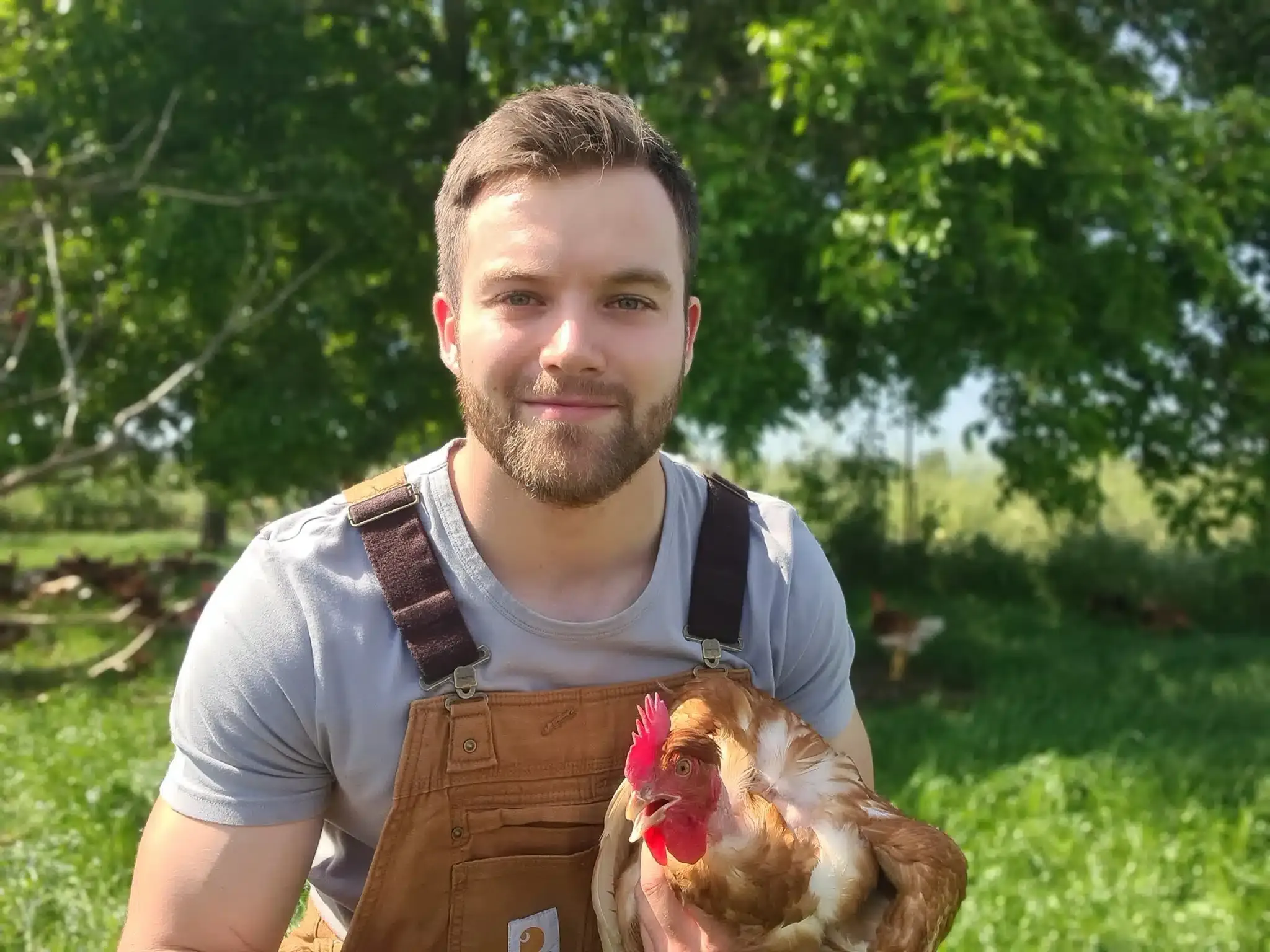 Un éleveur de la famille Pons tenant une poule dans les prés