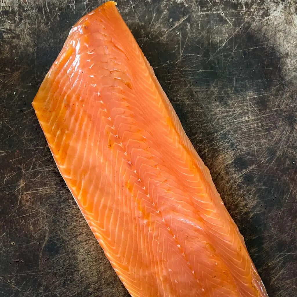 Un filet de saumon fumé entier paré, posé sur une planche