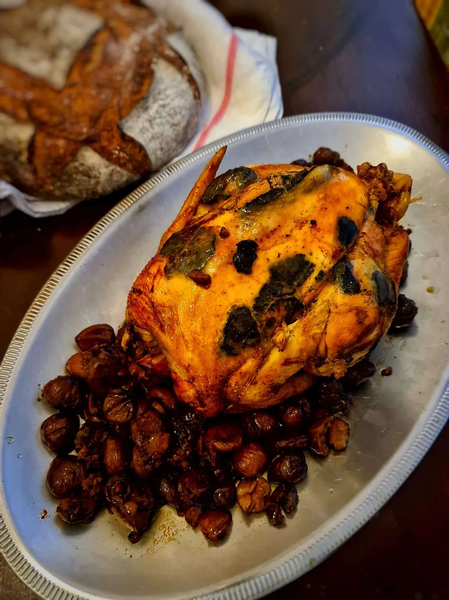 Une volaille rôtie servie sur un plat avec des châtaignes